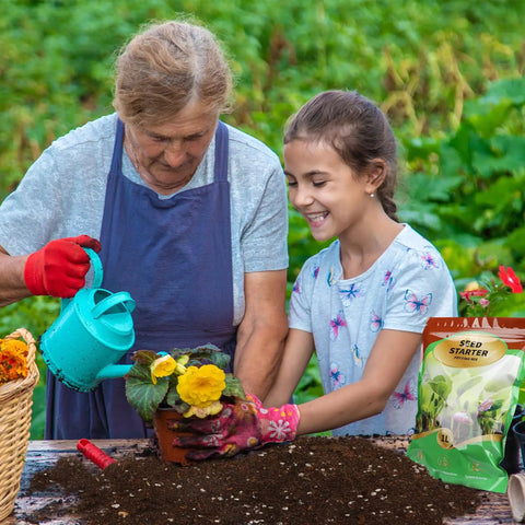 Elderly woman and young girl planting flowers with Ready To Grow Seed Starter Soil Mix 1 Qt for germination and early growth.