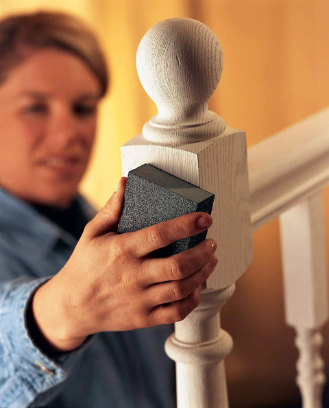Person sanding wood banister with Fine Grit Sanding Sponges 6-Pack For Smooth Finishes On Wood, Metal, And Plastic.