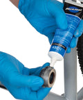 Park Tool ASC-1 anti-seize compound applied to bicycle bearing area; blue-gloved hands