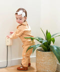 Child near outlet cover with cord shortener for baby proofing provides full outlet coverage keeps excess cords off the floor stores up to four feet of cords kid safe and easy to remove totally great for curious little ones in corner next to plant