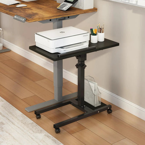 Black mobile adjustable height laptop desk on wheels, swiveling beside a main desk, with printer on 15 by 12 inch surface.