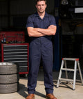 Heavy Duty Short Sleeve Coveralls For Men Work Jumpsuit Navy Cotton Polyester Blend Featuring Massive Storage Pockets Built Like A Rock Solid Workhorse For The Daily Grind worn by a man standing confidently in a garage.
