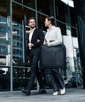 Two professionals with business travel garment bag in city