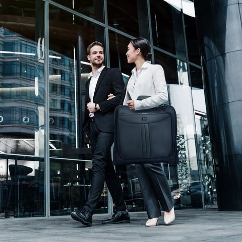 Two professionals with business travel garment bag in city