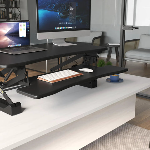 Standing Desk Converter 48 Inch Wide Sit Stand Desk Riser with Dual Gas Spring Handles on desk in office setup