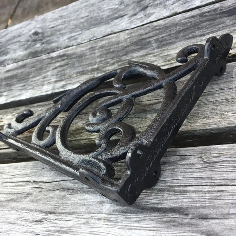Rock Solid Cast Iron Shelf Brackets Heavy Duty Wall Mount Braces Vintage Metal Corbels in black on a wooden surface.