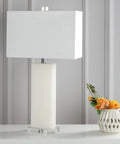 White Alabaster 27 Inch Rectangular Table Lamp With White Linen Shade on a table next to a vase with flowers