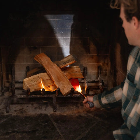 Person lighting wood in fireplace using Real Wood Pellet Fire Starter Pack 10 Count For Smokeless Outdoor Fire Pits And Indoor Fireplaces Easy Lighting