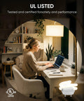 Woman working at desk with UL Listed 13W GU24 CFL Light Bulb 2700K Soft White 1000 Lumen Spiral, home office setting.