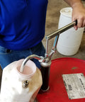 Guardian Lever Action Drum Transfer Pump for 16 to 55 Gallon Drums with 2 Inch Bung and Bushing in use, transferring liquid from red drum