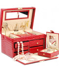 Red crocodile leather jewelry box with multiple compartments, earrings, necklaces, and a small mirror.
