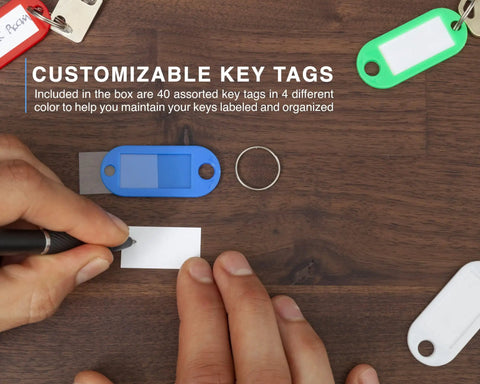 Person writing on label for customizable key tags with 40 Key Cabinet With Digital Lock Key Safe For Office And Valet Use nearby.