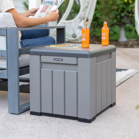 Versatile Outdoor Storage Cube Deck Box Doubles As Cozy Bench Seat And 25 Gallon Capacity Weather Resistant Patio Organizer, gray, with drinks and magazine.