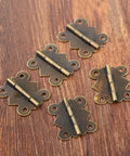 Five 20x25mm mini butterfly door hinges in antique bronze shown on a wooden surface, part of the 40 Pcs Mini Butterfly Door Hinges Set.
