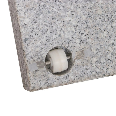 Close-up of Heavy Duty Granite Patio Umbrella Base With Handle And 2 Casters, showcasing the caster wheel embedded in grey stone.