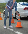 Person placing Four Pack 28 Inch Collapsible Traffic Cones With LED Light Reflective Collars Quick Pop Up Extendable Road Safety Cones beside car.
