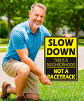 Man placing Set Of 3 Please Slow Down Signs For Neighborhoods With Metal H Stakes 12x8 Inch Plastic Double Sided Street Slow Signs