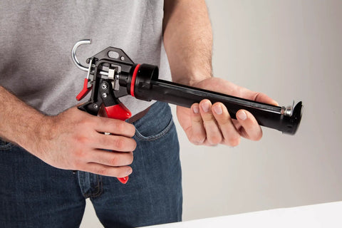 Person holding Extreme Duty 9 Inch Caulk Gun Workhorse with 26 to 1 Thrust Ratio and 950 lb Force, Revolving Barrel in hand