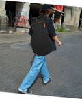 Person walking with a black Road Ready Portable Dumb Drum Bag For Silent Practice Pad Storage In Slick Oxford Fabric.