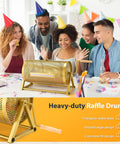 Front view of a gold perforated metal raffle drum, 15x7 in, holds 3,000 tickets; wooden turning handle and tripod stand