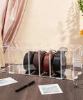 Top Shelf Slick Acrylic Belt Organizer With Removable Dust Cover Seven Compartment Clear Drawer Storage for Ties Belts Bow Tie Purse Socks with belts displayed.