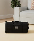 40L Military Tactical Duffle Bag for men with shoe compartment on beige carpet next to sofa, featuring durable black 900D polyester.