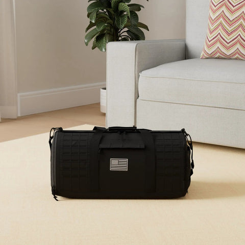 40L Military Tactical Duffle Bag for men with shoe compartment on beige carpet next to sofa, featuring durable black 900D polyester.