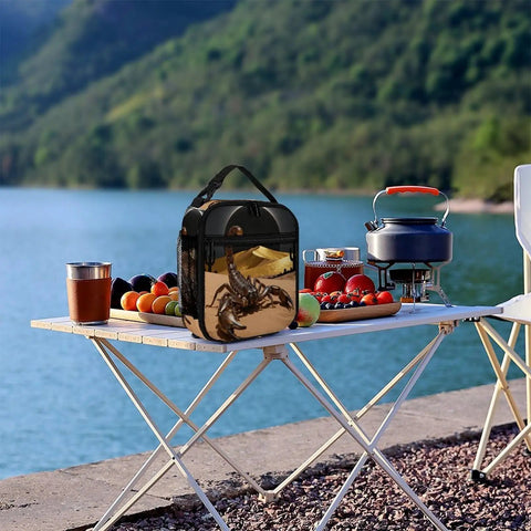 Desert Scorpion Eclipse Insulated Lunch Box on picnic table by lake with fruits and cooking pot, showcasing versatile outdoor use