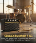 10W Wireless Portable Guitar Amp With Type C Rechargeable Battery in music studio, drums and microphone blurred in background.