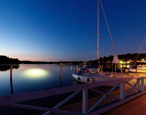 Sick Underwater Led Dock Light With Heavy Duty Fish Attraction Glow No Sweat Plug And Play Install Low Voltage Marine Safety And A Forty Foot Cord That Shines With Straight Fire Brightness For Night Fishing illuminating water near dock at dusk.