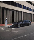 Black BMW parked at charging station on urban street, showcasing the modern design and eco-friendly technology.