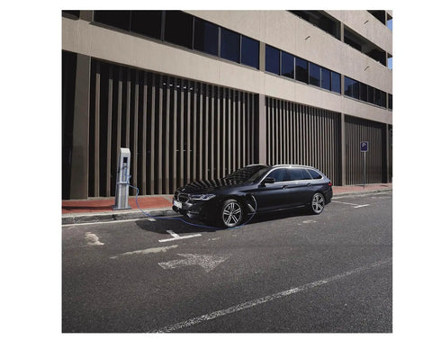 Black BMW parked at charging station on urban street, showcasing the modern design and eco-friendly technology.