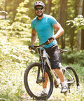Cyclist riding mountain bike on forest trail, wearing blue shirt and helmet