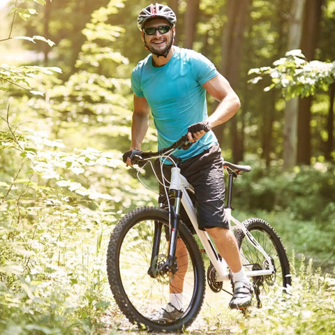 Cyclist riding mountain bike on forest trail, wearing blue shirt and helmet