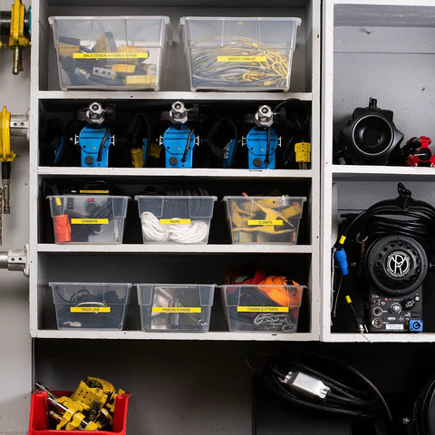 Organized shelving with labeled bins holding dimmers, clamps, ropes, and safety cables using Knockout Performance P Touch Pro Label Maker.