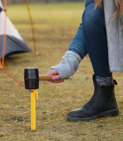 Durable Rubber Head Tent Peg Mallet With Stake Puller For Camping And Hiking in use driving stake into ground next to tent