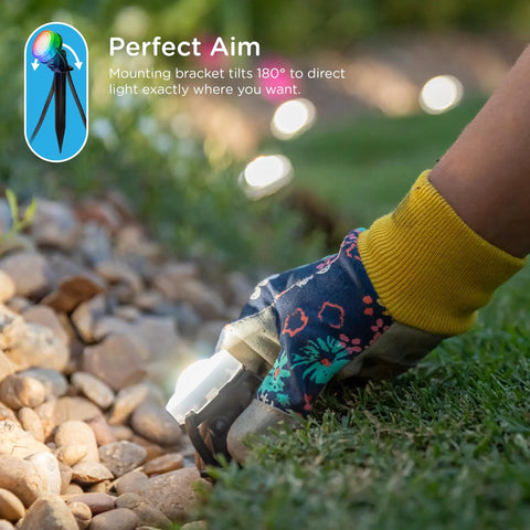 Person adjusting Vibe Eternity Garden Lights 50 Foot Outdoor RGBWIC LED Uplights Kit in a garden with stones and bright LEDs.