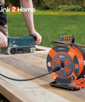 60 Ft Cord Reel With Four Outlets 14 AWG SJTW Cable Workhorse Heavy Duty shown on a wooden workbench with a power tool.