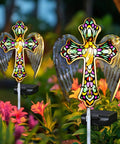 Solar Glass Cross Garden Stake Light With Angel Wings And Stained Glass Look placed among blooming flowers in garden