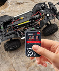 Hand holding RC Car ESC Programming Card With LED Programmer For 3660 Fusion Brushless Motors next to RC car chassis