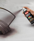 Person spraying Killer Hammered Finish Spray Paint In Deep Cocoa Brown on metal object, 12 oz aerosol can.