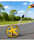 MZZKFC Hand Push Mechanical Measuring Wheel with Non-Slip Handle on a path, showcasing a yellow wheel and aluminum handle.