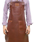 Man wearing Leather Grill Master Apron With Cross Back Straps Heat Resistant Full Grain Leather For BBQ Woodworking Unisex Brown.