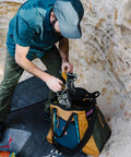 Man placing hiking boots into Monster 48L Gear Hauler Tote Bag In Recycled Nylon Free Standing And Abrasion Resistant.