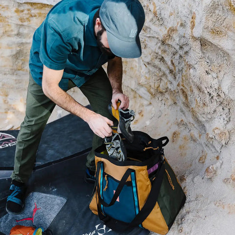 Man placing hiking boots into Monster 48L Gear Hauler Tote Bag In Recycled Nylon Free Standing And Abrasion Resistant.