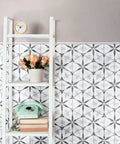 Dope Bardiglio Hex Flower Porcelain Tile 7x8 for floor and wall, shown in living area with decorative shelving and plant.
