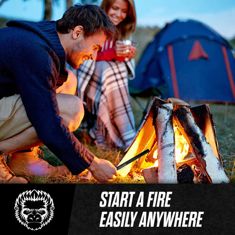 Person using Ferro Rod Fire Starter Kit with Paracord and Scraper at campsite beside a glowing campfire.
