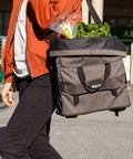 Person carrying 4 In 1 Dayliner Box Bag 20 Liter Water Resistant Rolltop with shoulder strap, filled with groceries.