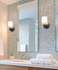 Kira Home Phoebe 8" Modern Industrial Wall Sconce for Bathroom Vanity, Pack of 2 mounted beside a bathroom mirror.