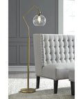 Modern Floor Lamp With Glass Shade And Angular Arm In Antique Brass, 61 Inch Tall next to gray button-tufted furniture